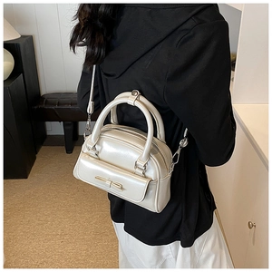 Detail of a pearl white Boston bag with bow pocket and detachable strap on a model