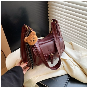 Détail du sac à bandoulière en cuir brillant bordeaux avec breloque ours et boucle métal