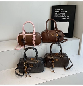 Selection of retro bowling handbags in pink, coffee, and black on a white marble display