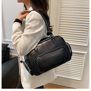 Full side view of a minimalist black leather shoulder bag styled on a female model