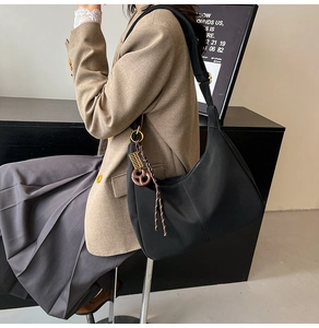 Detail of black nylon hobo bag featuring a creative abacus and heart charm on the shoulder strap
