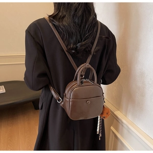 Brown leather backpack for women with teddy bear charm shown as back view on model