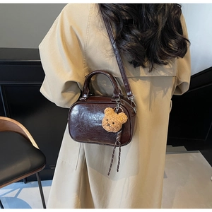 Détail d'un mini sac à main marron rétro avec texture brillante et breloque ourson