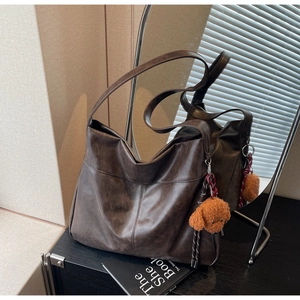 Detail of dark brown faux leather tote bag with vertical stitching and dog charm