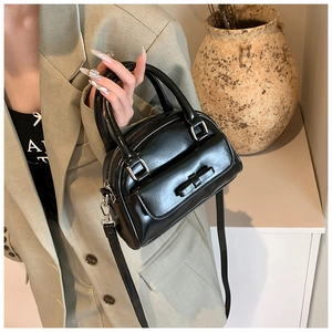 Detail of black Boston bag with decorative bow and shiny faux leather texture