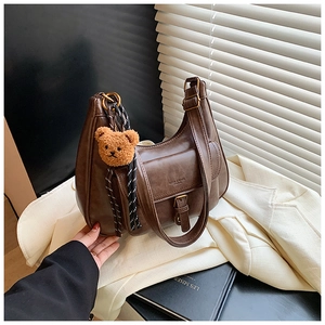 Détail du sac hobo vintage marron avec breloque ours sur fond blanc élégant