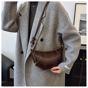 Detail of dark brown leather croissant bag with knotted strap and quilted seam design