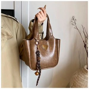 Close-up of vintage brown leather bucket bag with metallic triangle logo and tassel detail