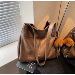 Close-up of large brown PU leather tote bag featuring a cute plush puppy pendant