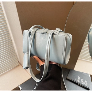 Detailed macro view of the light blue glossy leather texture and zipper of the shoulder bag