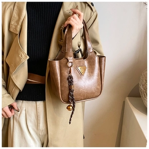 Macro view of retro brown bucket bag with gold triangle logo and weave ornament