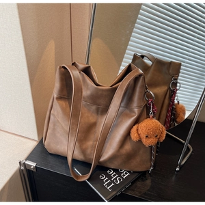 Brown faux leather hobo bag with vertical stitching and cute teddy bear charm detail