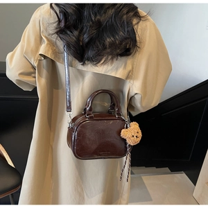 Détail du mini sac en cuir ciré marron foncé avec pendentif ours en peluche sur modèle
