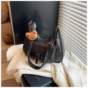 Détail du sac à bandoulière noir vintage avec finitions dorées et charm d'ours en peluche