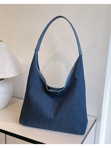 Sac fourre-tout minimaliste en denim bleu foncé avec large bandoulière sur bureau