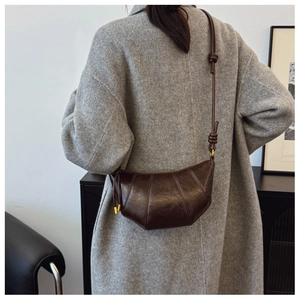 Detail of vintage brown crescent bag styled on a grey wool coat with knotted strap