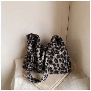Macro detail of plush leopard print faux fur tote bag resting on a vintage book
