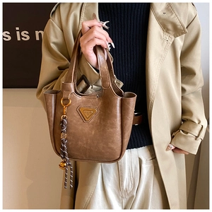Detail of vintage brown leather bucket bag with triangle logo and bell charm accessory