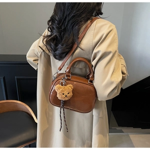 Détail du sac à main en cuir verni marron caramel avec double zip et pendentif ourson