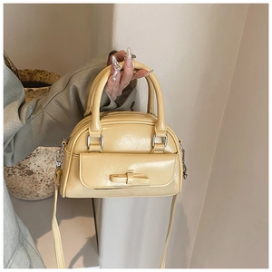 Close-up of cream Boston bag featuring a bow detail and glossy wrinkled leather texture