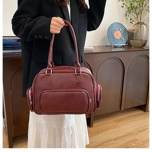 Detail of burgundy leather shoulder bag with large front zipper and silver hardware accents