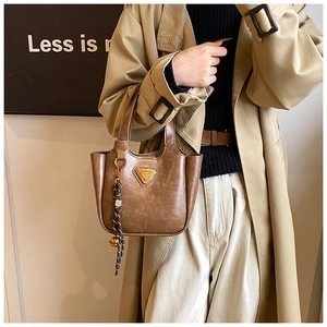 Detail view of vintage brown bucket bag with triangular logo and woven tassel charm