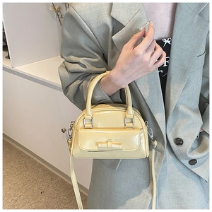 Close-up of a cream bow handbag with silver hardware and adjustable shoulder strap