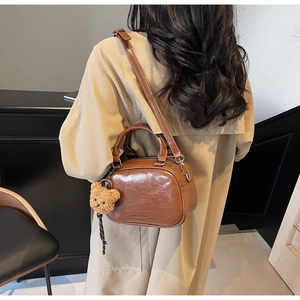 Détail du sac bowling vintage en cuir marron brillant avec pendentif ours peluche