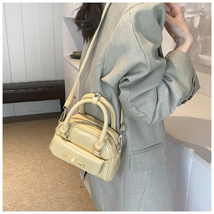 Close-up of cream Boston bag with bow detail on a green suit outfit style