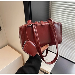 Close-up of burgundy patent leather box bag with silver zippers and mini coin purse