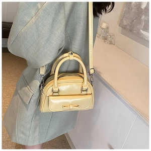 Detail of cream Boston bag featuring a bow decoration and a front slip pocket