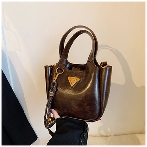 Detail of dark brown leather bucket bag with polished finish and metal triangle logo