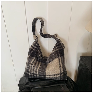 Detail showing the bouclé texture and decorative knotted handle of this plaid tote bag