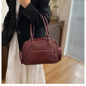Detail view of the large deep red shoulder bag with side zippers shown on a model