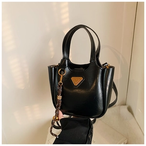 Detail of black leather bucket bag with gold triangle logo and braided rope accessory