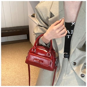 Detail of red patent leather Boston bag with bow decoration and silver metal hardware