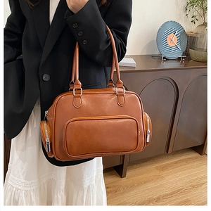 Caramel large capacity shoulder bag with multiple zippers shown in lifestyle scene
