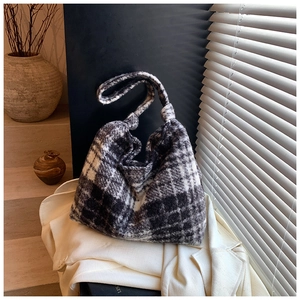 Close-up detail of soft plaid fleece tote bag on a white blazer with elegant lighting
