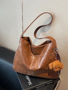 Vintage brown large capacity tote bag with teddy dog plush charm on a textured background