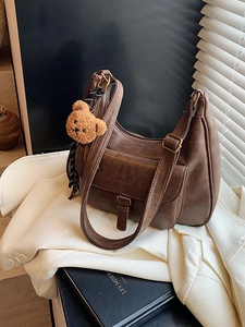 Sac hobo vintage en cuir marron mat avec breloque ours et large bandoulière sur blazer