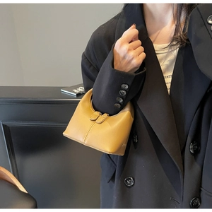 Chic khaki mini handbag in matte leather worn by a model in a black blazer