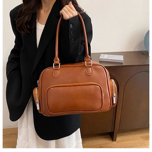 Detail of a brown PU leather shoulder bag with multiple zippered pockets and silver hardware