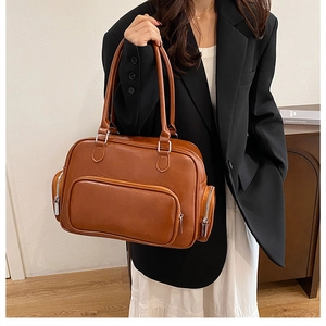 Close-up of a vintage brown leather Boston bag with functional side zipper pockets