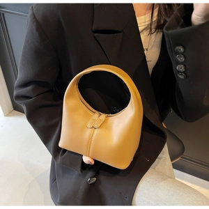 Detailed macro view of minimalist tan leather handbag with smooth matte finish and top zipper
