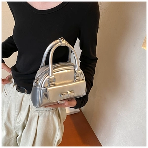 Detail of silver metallic handbag with bow decoration and glossy reflective finish