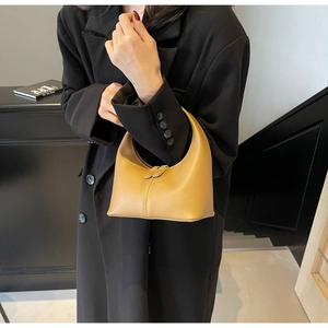 Detail of a minimalist mustard yellow crescent handbag with stylish vertical stitching