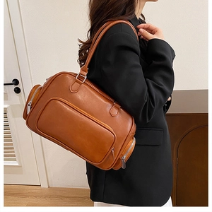Detailed texture of a brown vintage Boston bag with side zippers on a modern blazer