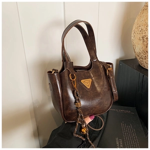 Detail of vintage brown bucket bag with triangular metal logo and tassel charm
