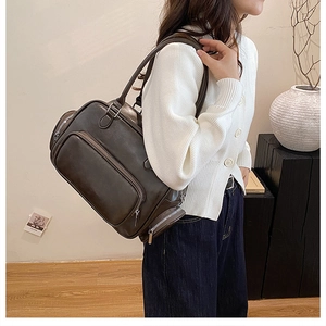 Detail view of large capacity dark brown leather shoulder bag with silver zipper