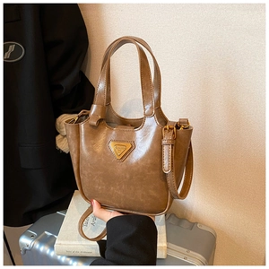 Macro shot of vintage brown oil wax leather bucket bag with gold triangular metal hardware